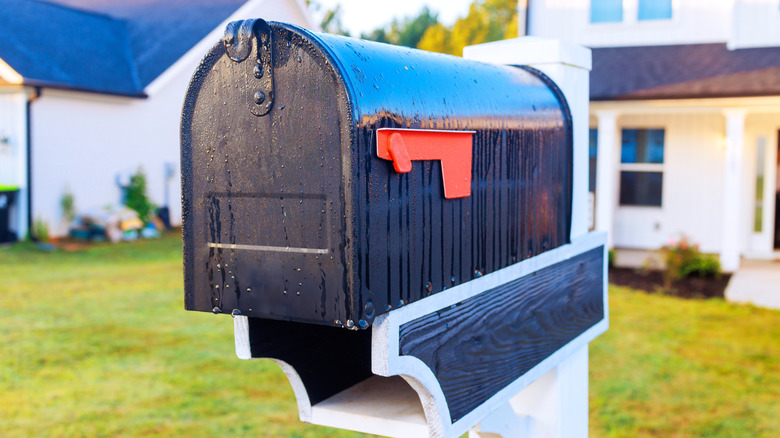 Black mailbox in yard in front of home