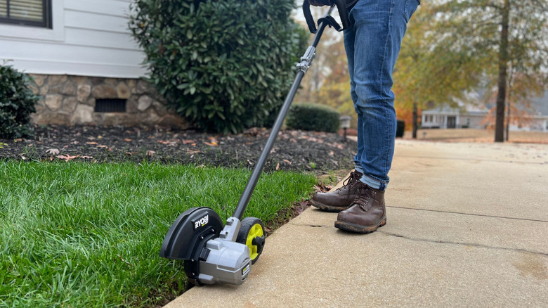 The Ryobi 40V brushless lawn edger being used by a person wearing jeans and boots