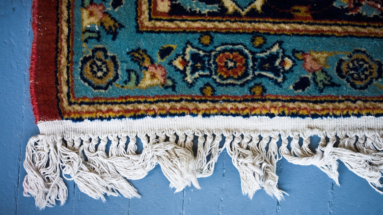 The edge of a red and blue rug with fringing