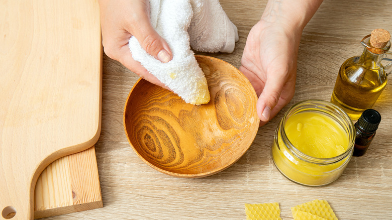 Close up view of person polishing wood bowl with beeswax