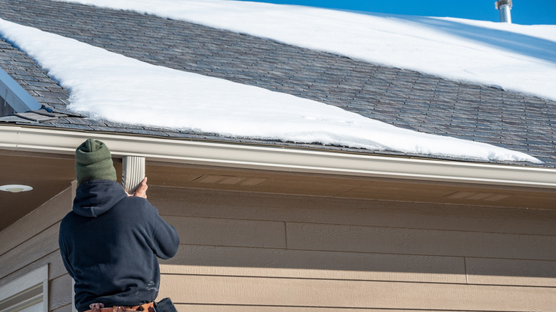 Man inspecting a roof with patchy snow