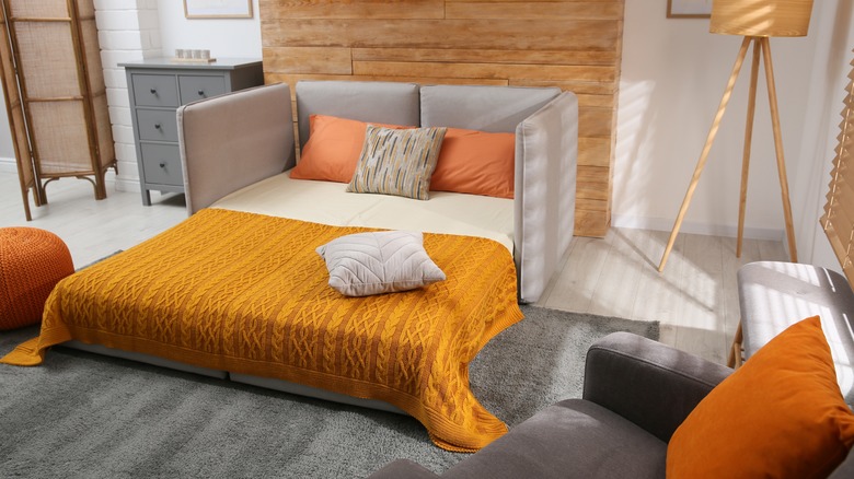 Sofa bed against wooden wall