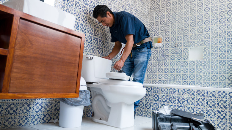 A plumber working on a toilet in a bathroom