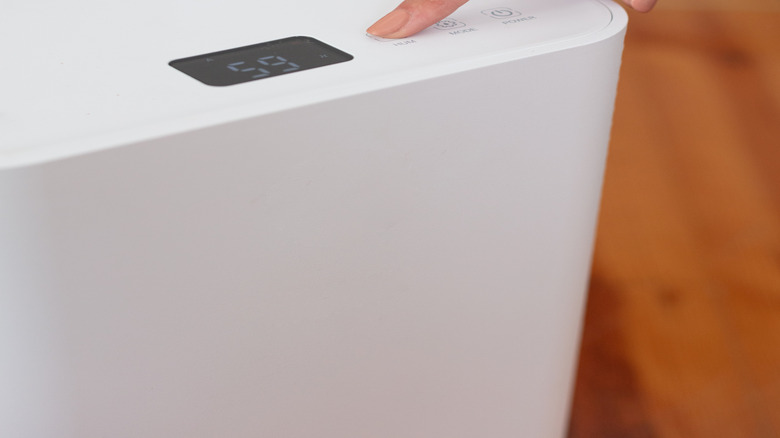 Hand pushing button on dehumidifier