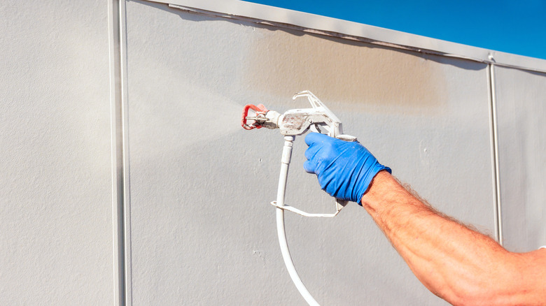 A man using an airless paint sprayer