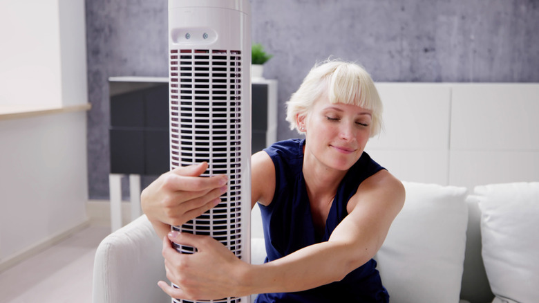 Woman hugging a white tower fan