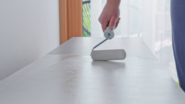 A woman painting an MDF worktop prior to creating a soapstone effect