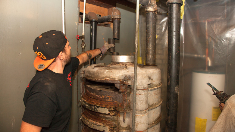 A maintenance crew replaces pipes on an old gravity furnace.
