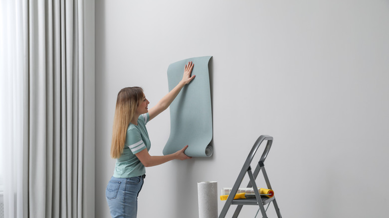 Woman hanging a sheet of wallpaper