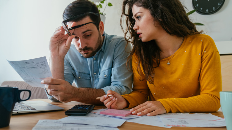 A young couple looks worried while surrounded by bills