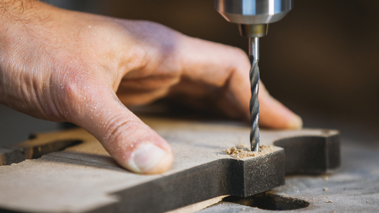 Person drilling hole in wood