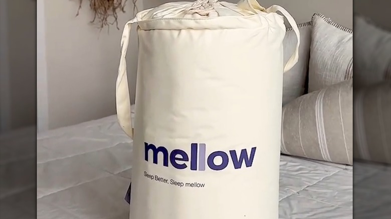 MarshMellow Comforter rolled inside of a fabric bag and sitting on a bed