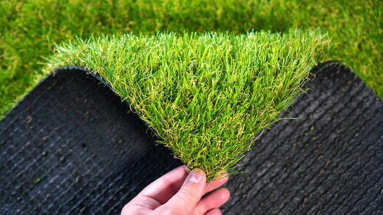 person inspecting roll of artificial turf