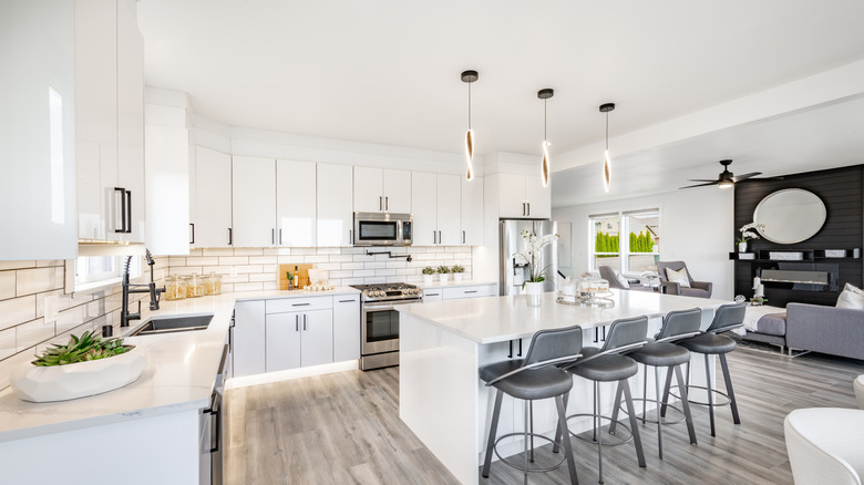 Modern contemporary home with staged interiors in soft grays and whites, featuring vinyl flooring, sleek cabinets, and bright sky-filled windows.