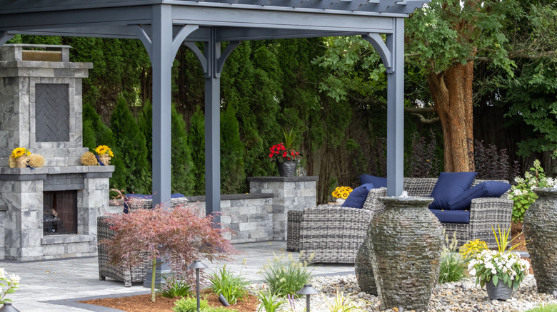 A modern stone patio with a fireplace and wicker patio set.