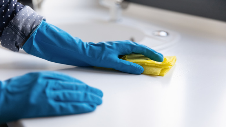 A person cleans a white bathroom countertop