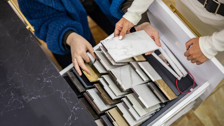 Two people look through small countertop samples in a store drawer