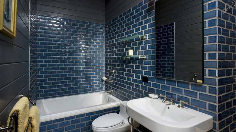 A bathroom filled with dark paneling and blue tiles