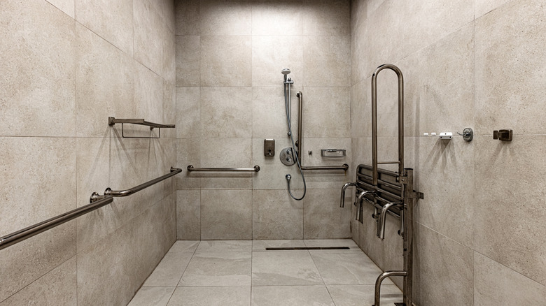 A large shower filled with the same colored tiles on the floor and sides with a soft light