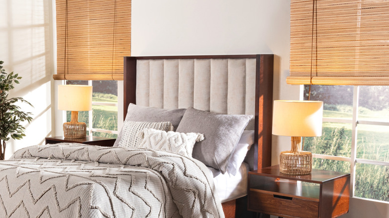 Bed placed between two windows, featuring a headboard with a fluted fabric texture and dark wood frame
