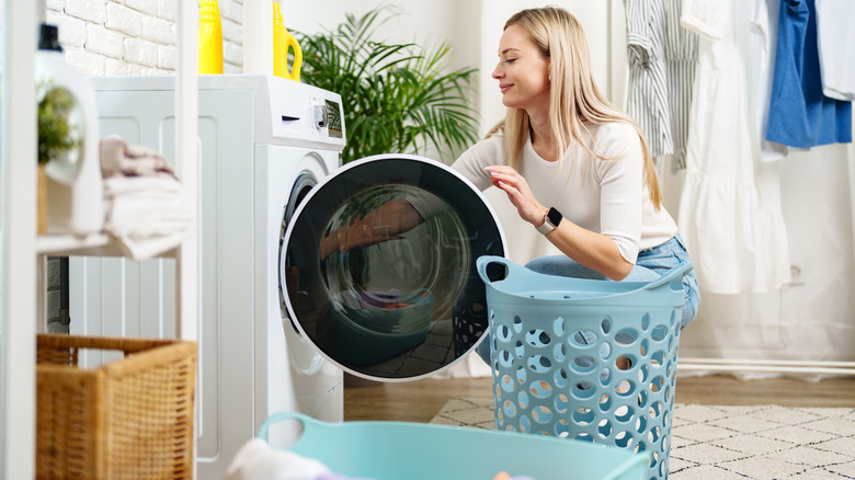 Woman taking laundry out of washing machine into a basket