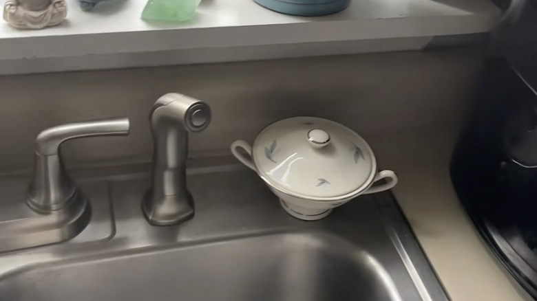 Vintage dish on the side of a sink with a sink strainer inside.