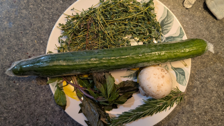 Plate of veggies after one week in fridge, showing Thai basil, thyme, an English cucumber, and a mushroom