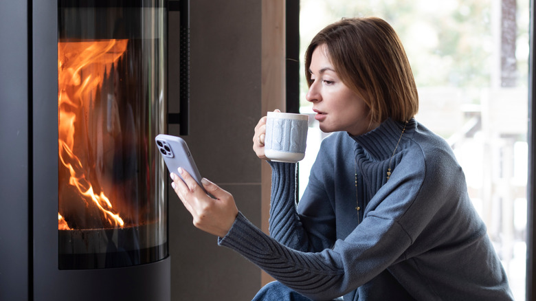 Person drinking tea and relaxing in front of a gas fireplace