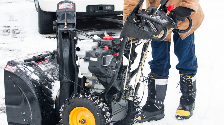 person fixing part of snow blower
