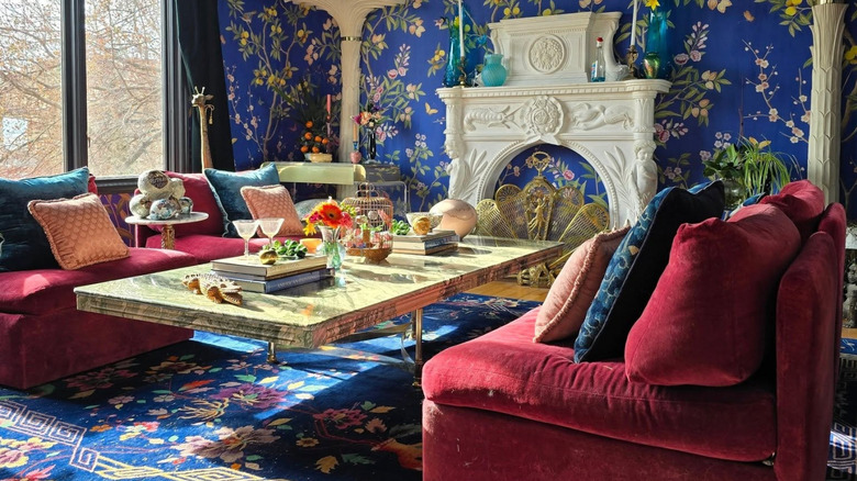 Room with red seating, chinoiserie wallpaper, and accents