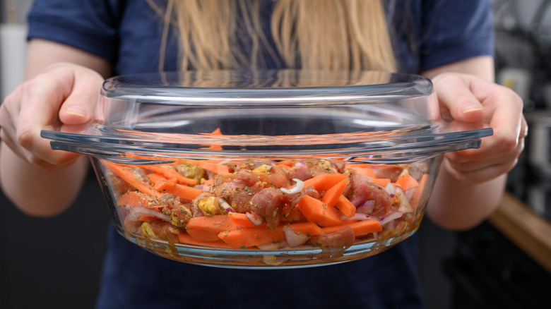 A woman holding a glass baking dish full of food