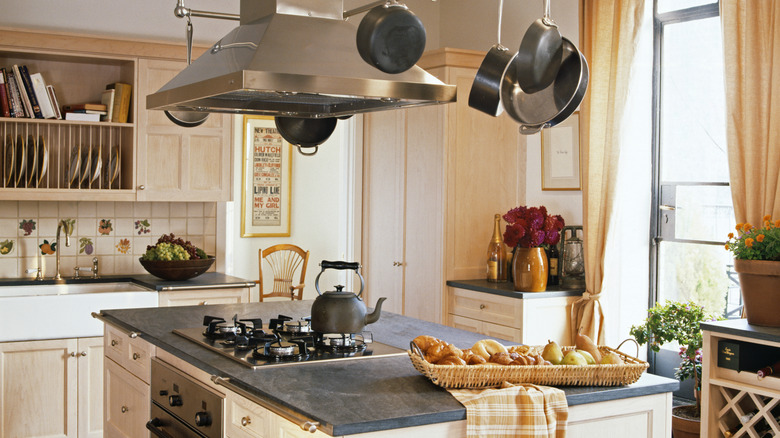 retro style kitchen with central island and stainless steel hood, farmhouse sink, and rustic tiles