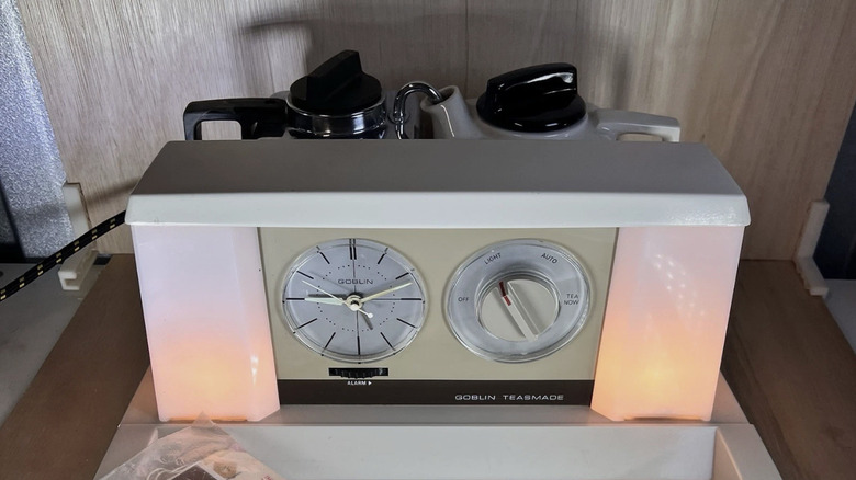 A vintage Teasemade machine with lights on either side of the alarm clock