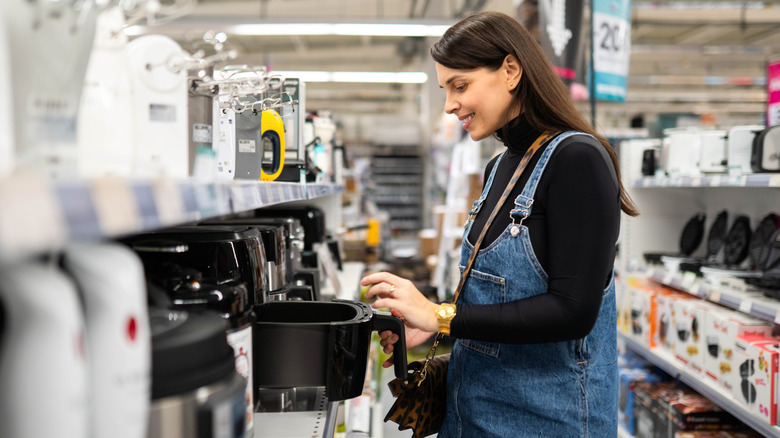 A woman browsing the aisles of a store and shopping for small kitchen appliances