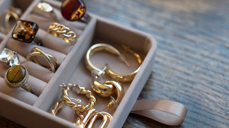 A gray velvet jewelry box filled with rings and earrings