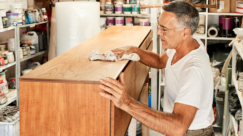 Man wiping down a wooden chest