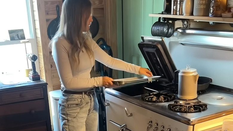 A woman demonstrates how to use a vintage Chambers gas range.