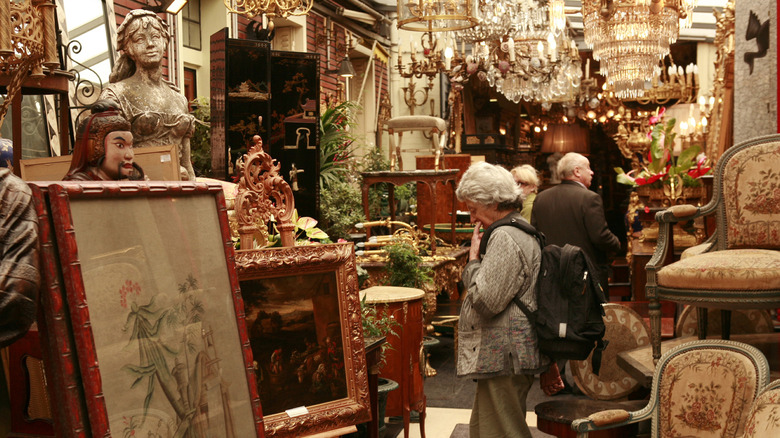 Shopper peruse the artwork and other home decor items in a crowded antique store.