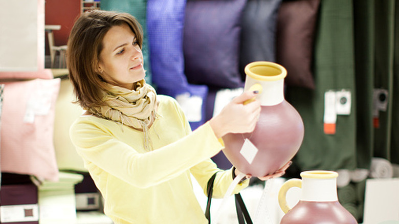 A woman selecting a ceramic vase for purchase