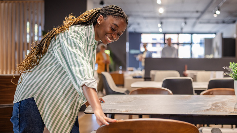 Woman smiling while looking at a table and chairs in a furniture store.