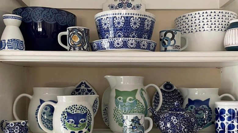 Collection of Arabia Finland dishware items sitting on kitchen shelves.