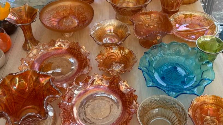 A table of ornate carnival glass pieces in orange, pink, blue and green