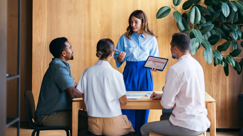 People sitting around a table with a wood paneling background