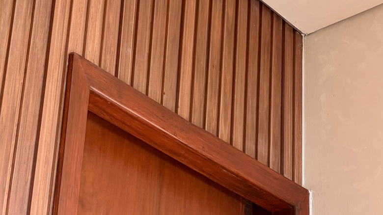 Slatted wood paneling installed above a doorway on a wall