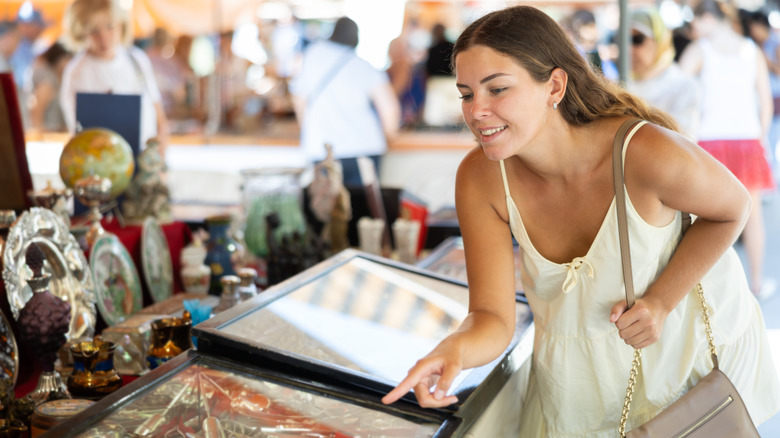A woman looking at silverware in a case at a flea market