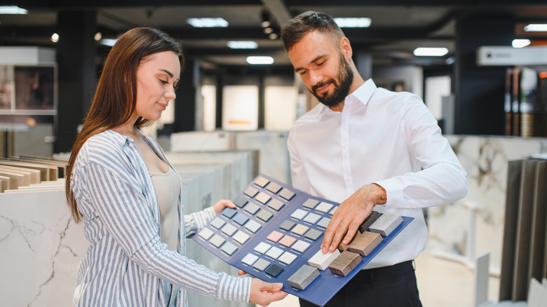 A salesman showing a woman a variety of porcelain tile options