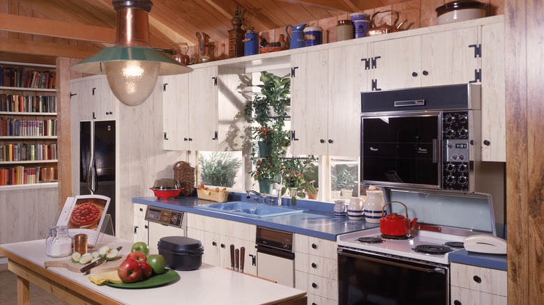 1980s kitchen interior with white cabinets, blue countertop, and kitchenware on display