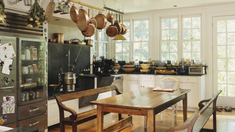 Hanging kitchen utensils and cookware on a ceiling rack in a modern kitchen.