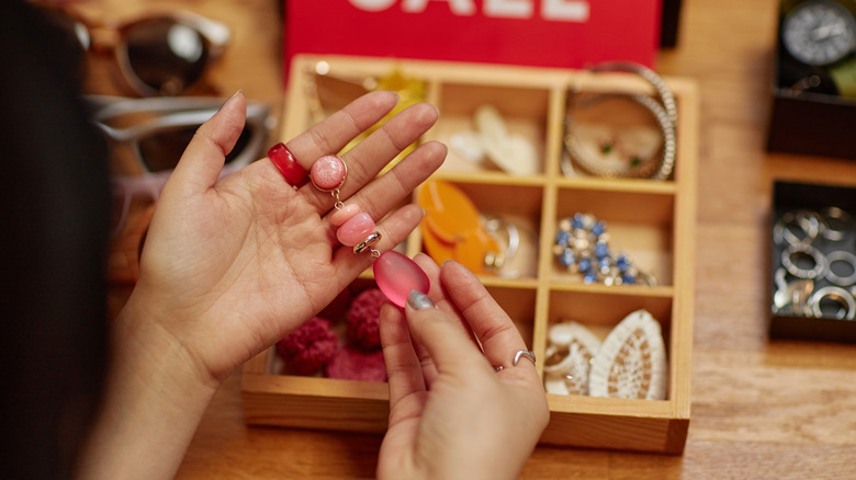 Woman holding pink jewelry at a thrift store