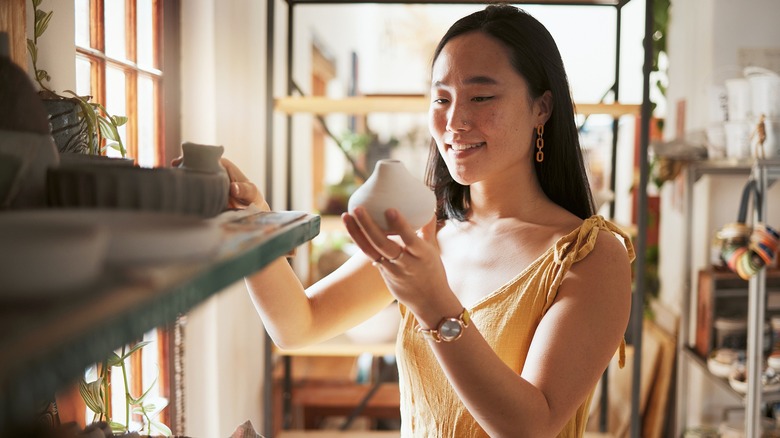 Woman smiling at a piece of pottery while shopping